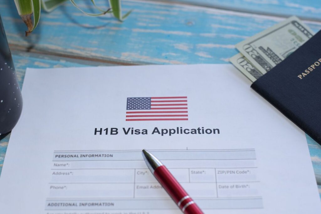Photograph of a Passport, a pen, and a H1B Visa Application